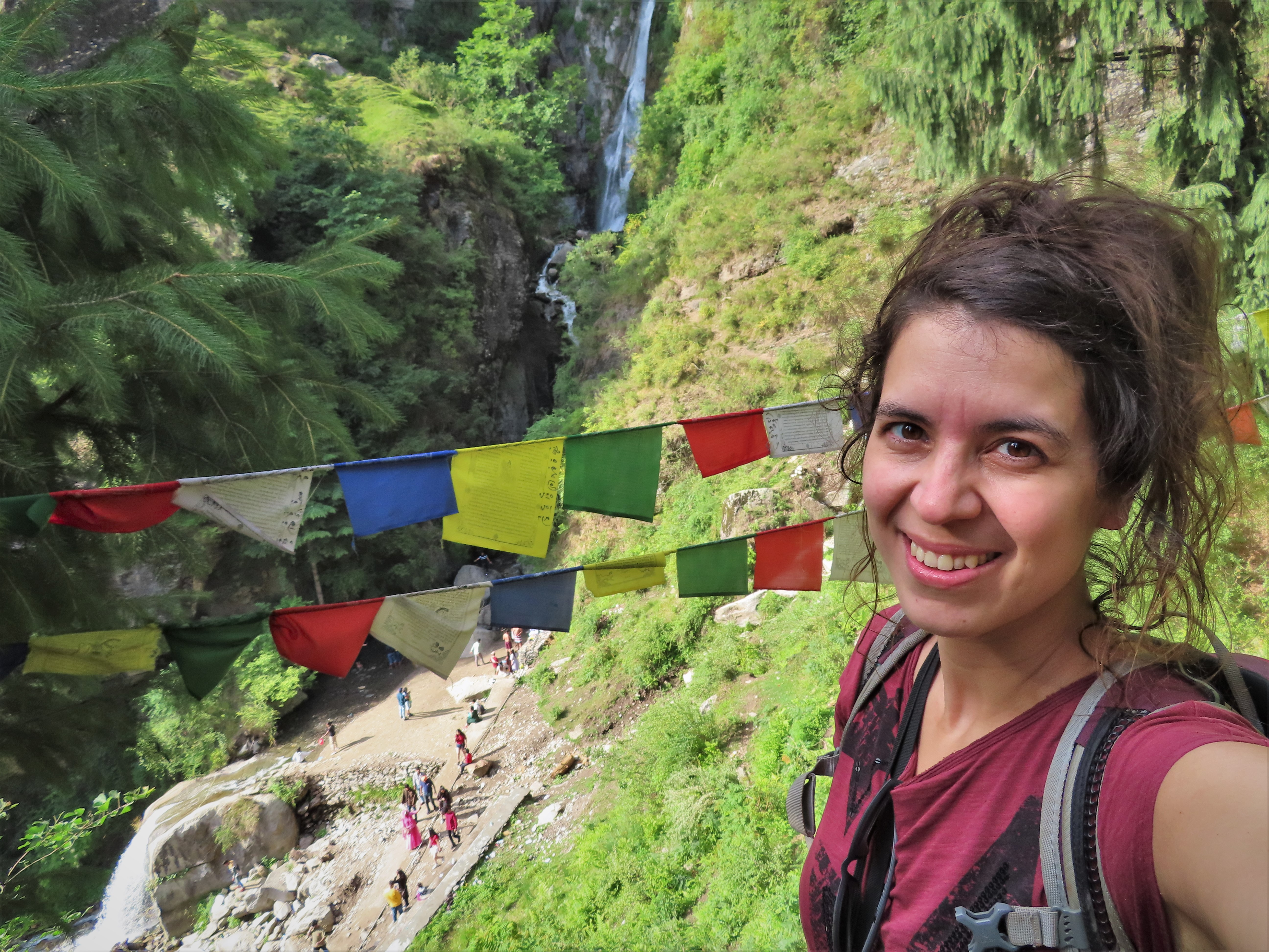Me with Buddhist prayer flags and the lower Jogini waterfall in the background in Vashisht, northern India.